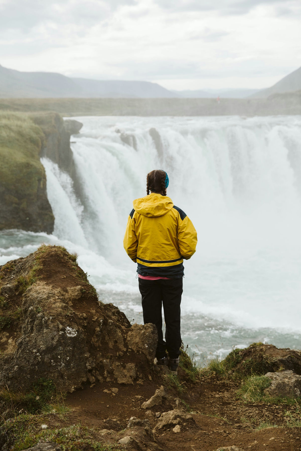 Woman stands in front of waterfall